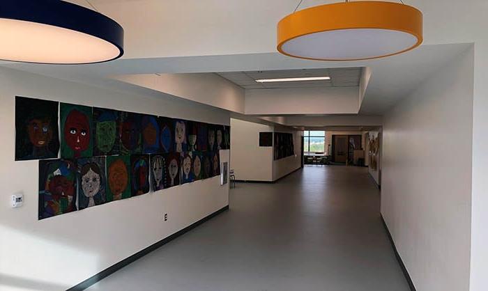 a hallway with round ceiling lights and children's artwork on the wall