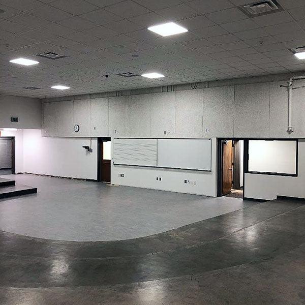 a large room with white boards on one wall and partial carpet in a curved space