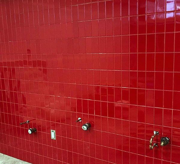 a red tiled wall with pipes