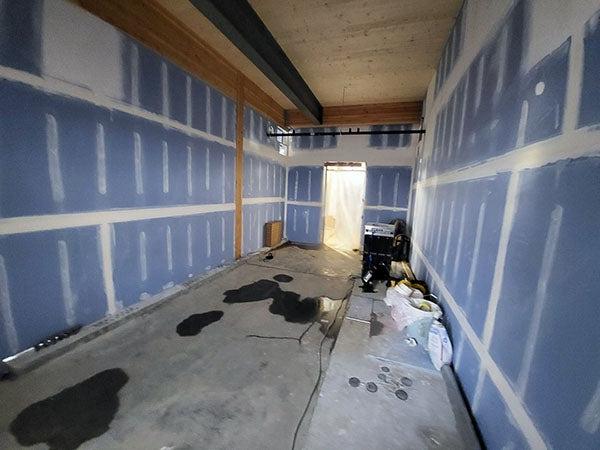 a narrow room with wallboard and wallboard tape and mud on walls