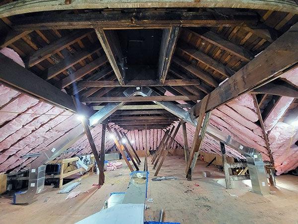 inside of a building with the wood framing showing and pink insulation in parts of it