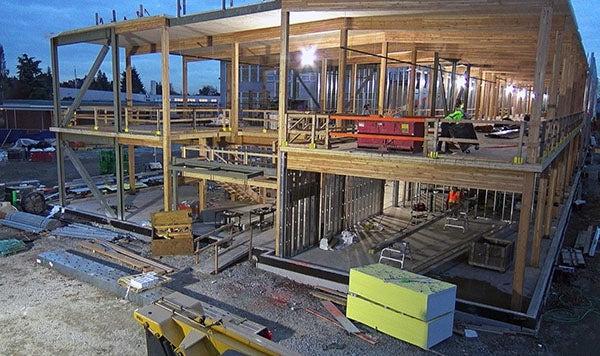 a two story building under construction with no exterior walls, wood beams, and interior metal studs