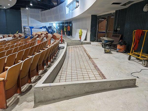 a concrete floor behind theater seats has a short wall on three sides with a grid inside