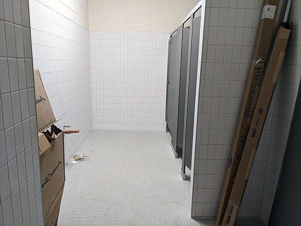 white tile walls with three toilet stalls on the left