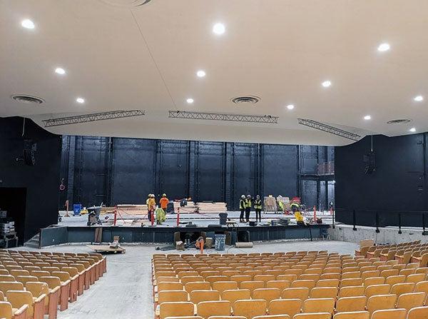 an auditorium with theatre seats with construction workers on the stage