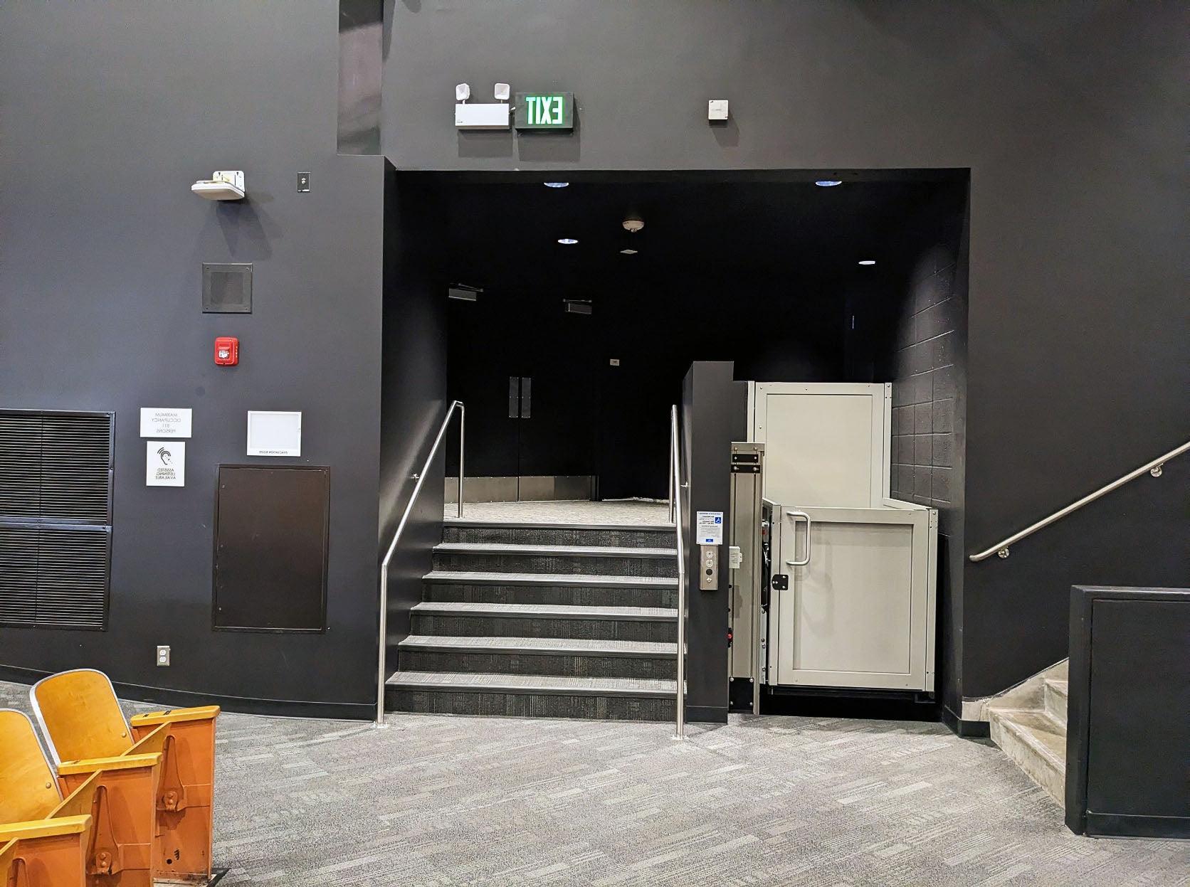 a mobility lift is shown next to a short set of six stairs with black walls around both