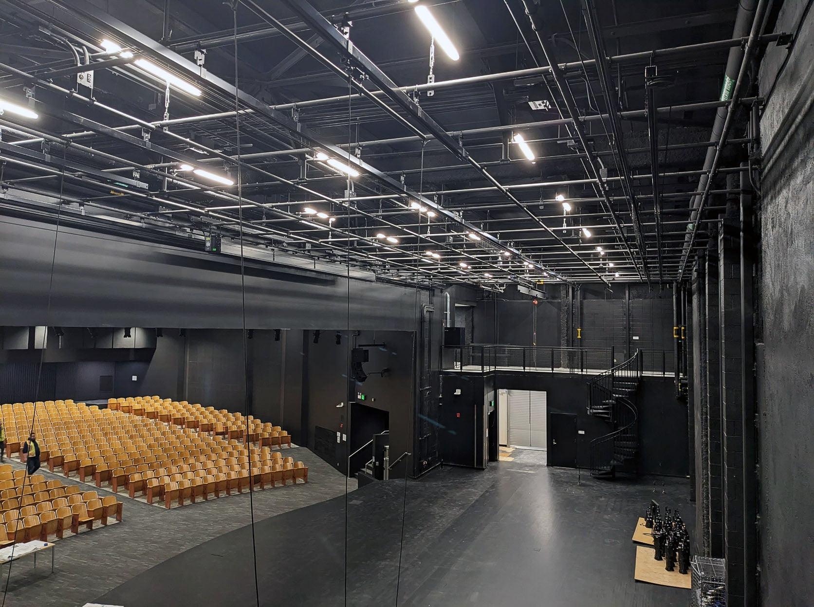 a grid of rigging hardware is shown above a stage with a view of the auditorium audience area