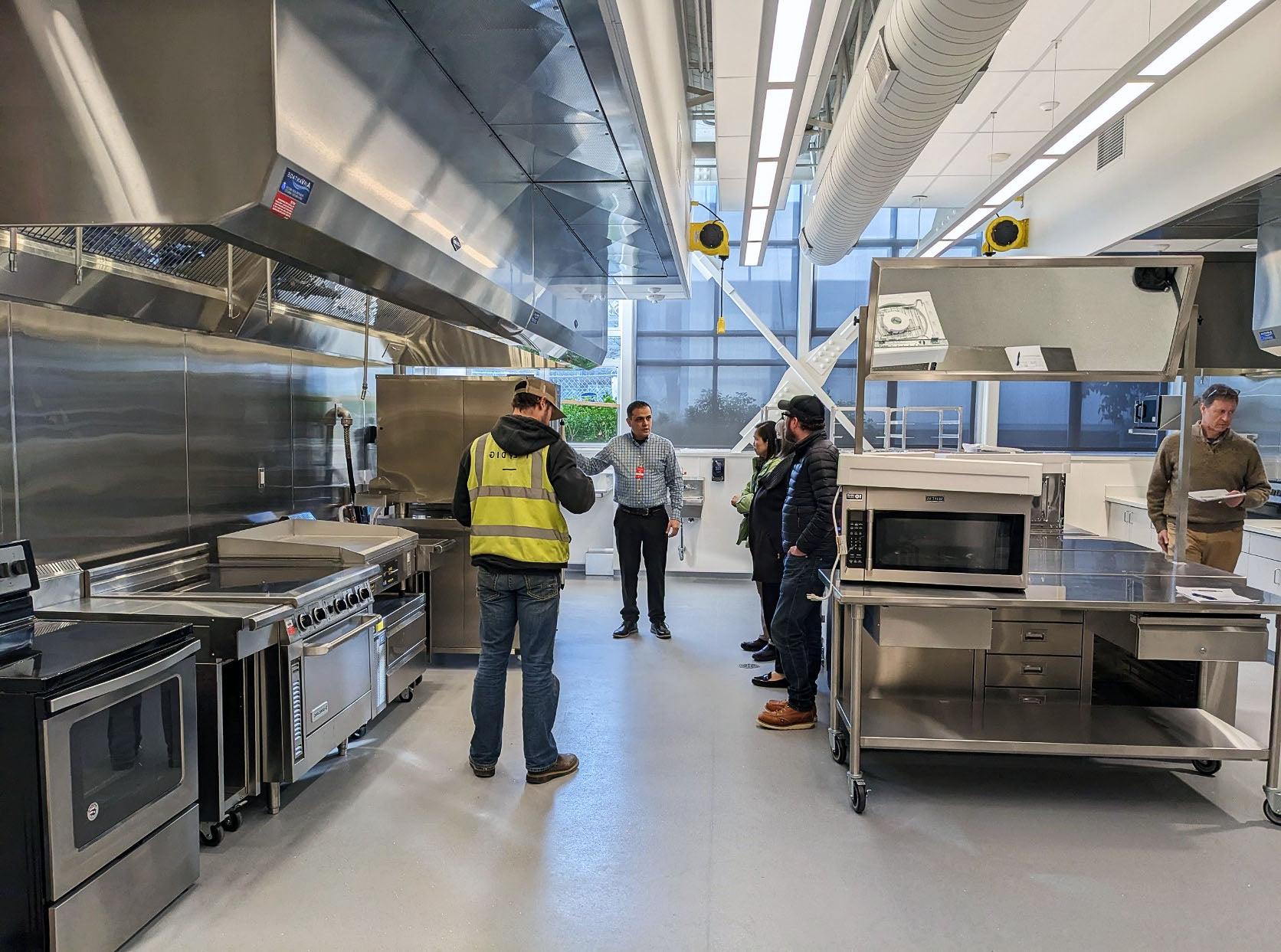 a group of people look at commercial size stainless steel cooking equpiment