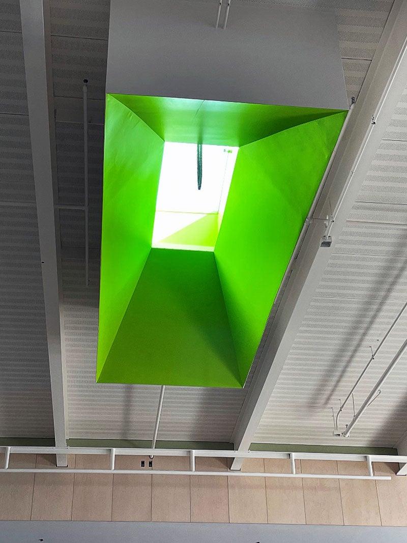 looking up to a high ceiling that has a skylight framed in bright green