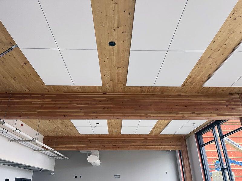 a ceiling with wood between tiles and large wood beams