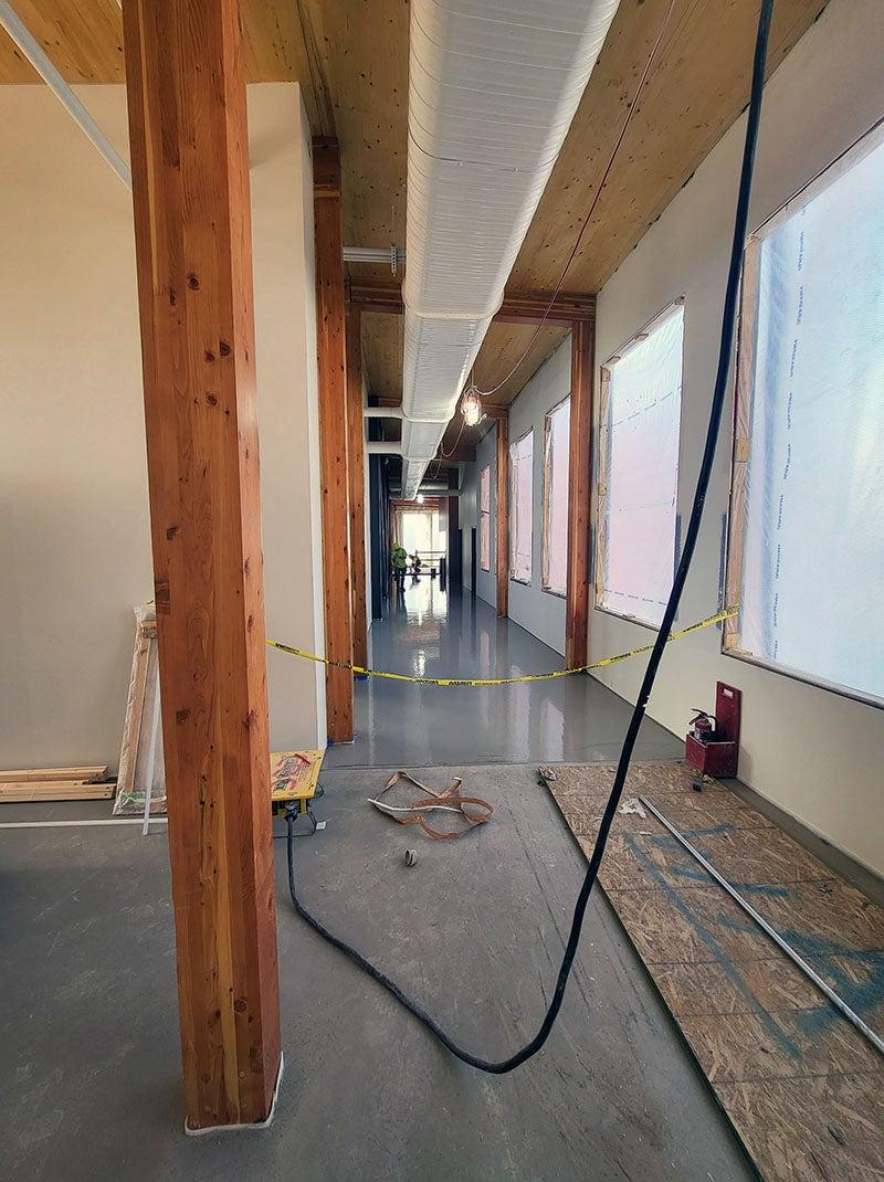 a shiny concrete floor in a hallway that is taped off with construction tape