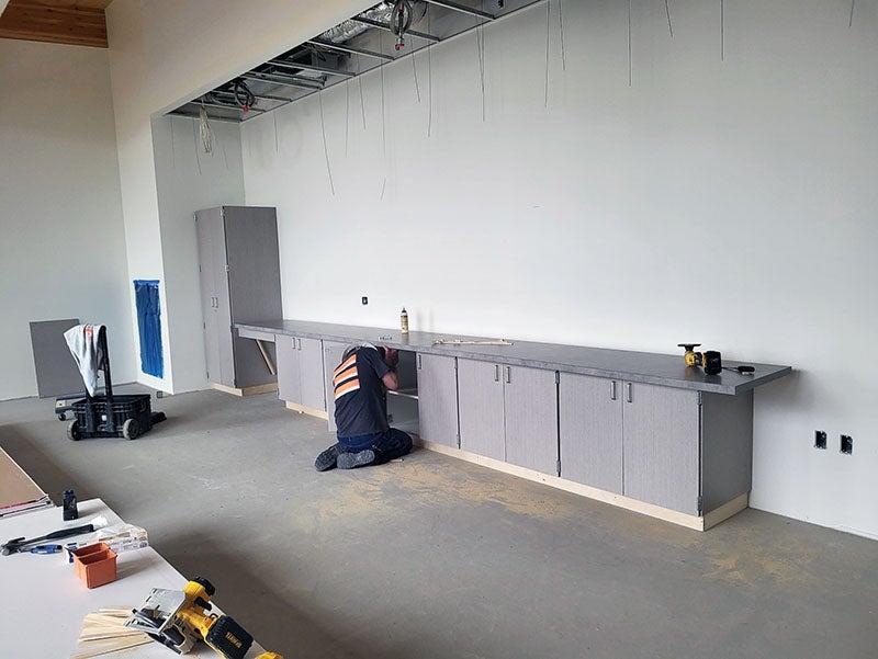 cabinet and counter top being installed by a worker in a large room
