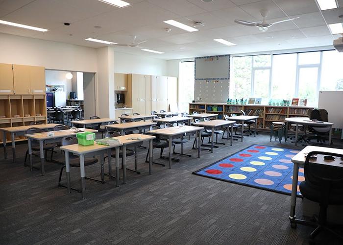 a classroom with desks in rows and an area rug with colored circles