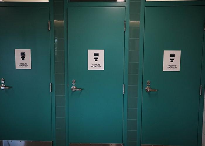 3 teal-colored doors have a toilet icon and say student restroom